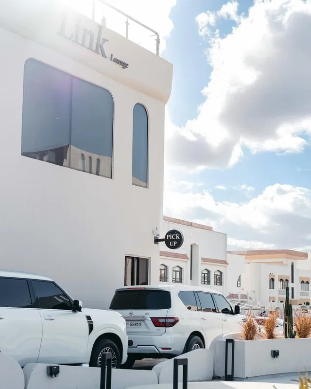 Link Lounge under a blue sky, cars parked in front