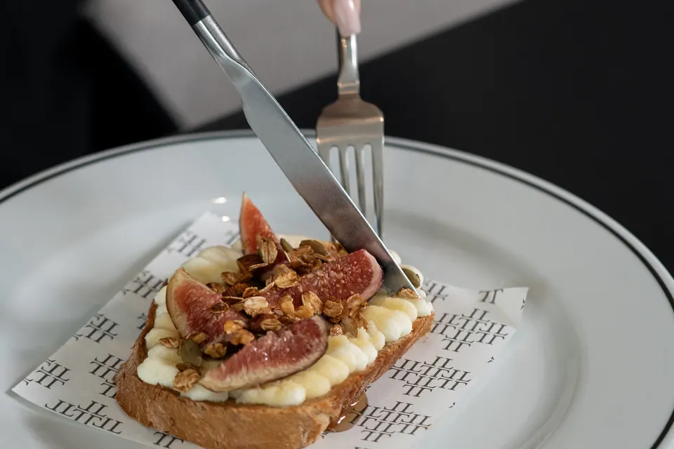 A honey fig tartine being cut at the table